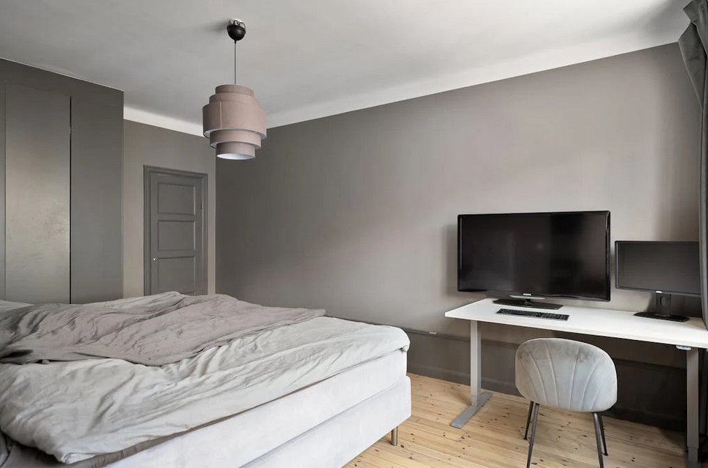 A dark colored bedroom, dark walls with light accent trim and furniture, a go to standard for studio decor ideas