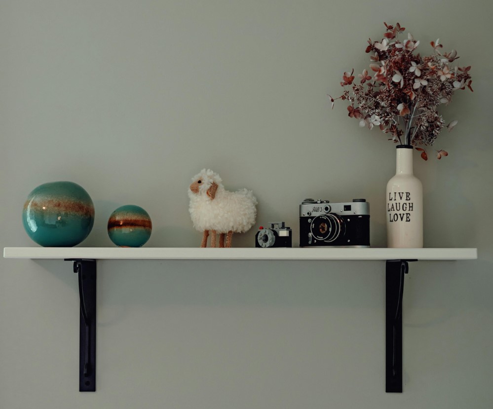 Floating wall shelf with various decorations and bottled plant