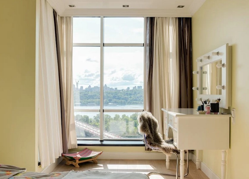 A small bedroom with a large window, during the day time