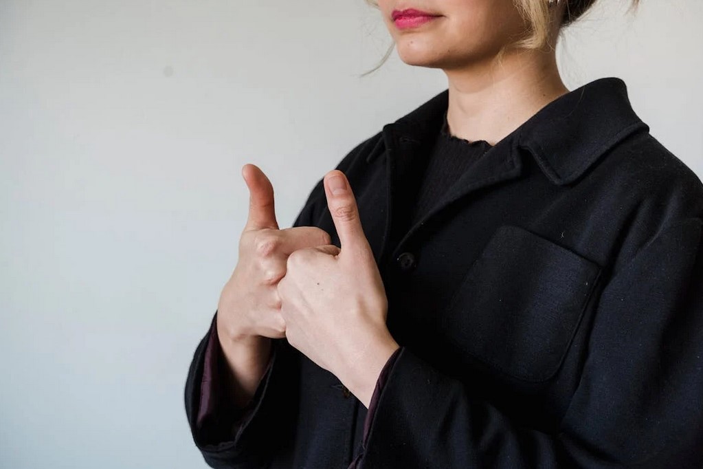 Woman in a black coat giving two thumbs up