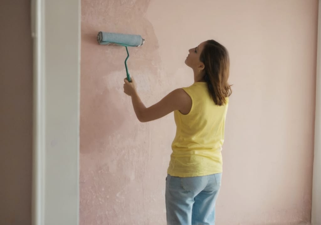 Woman standing painting her walls a pink salmon color